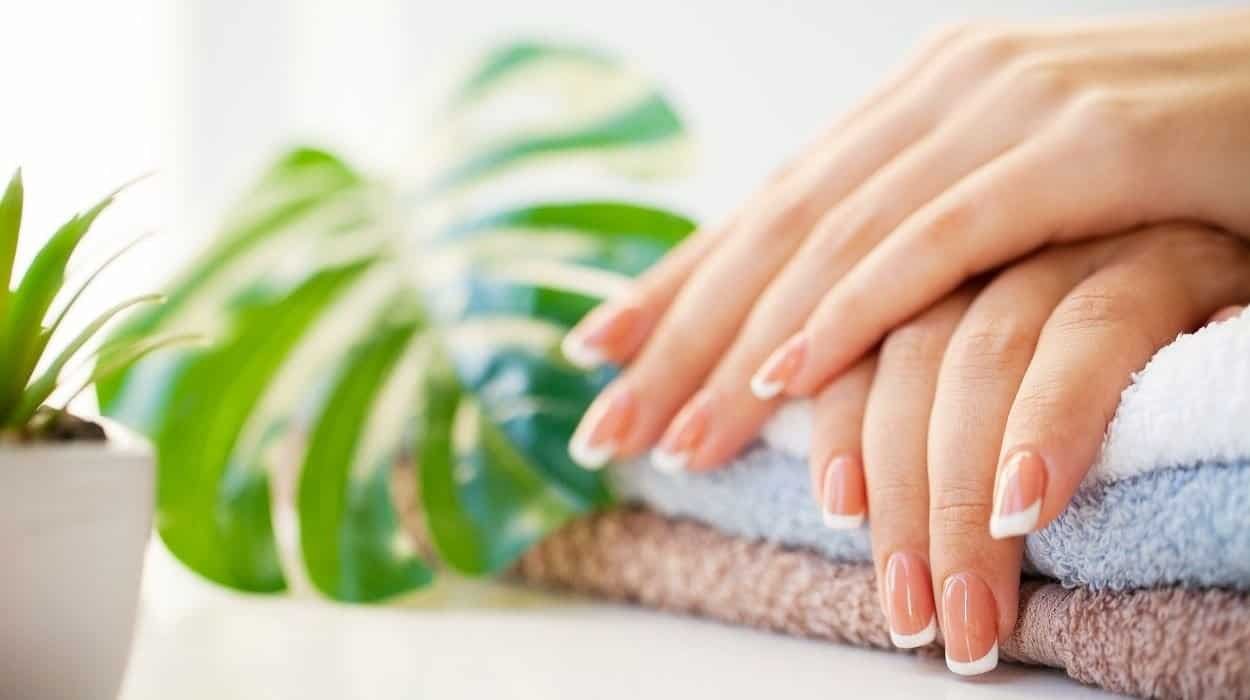 Signs of healthy nails showing smooth pink nail beds, natural shine, and hydrated cuticles compared to brittle nails with ridges and white spots indicating vitamin deficiency.